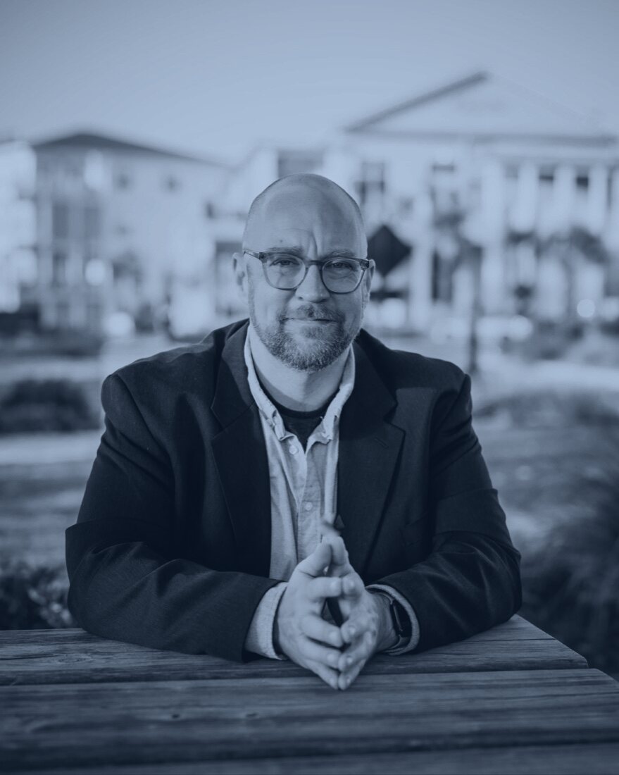 Clay Johnson, seated at a table, hands folded